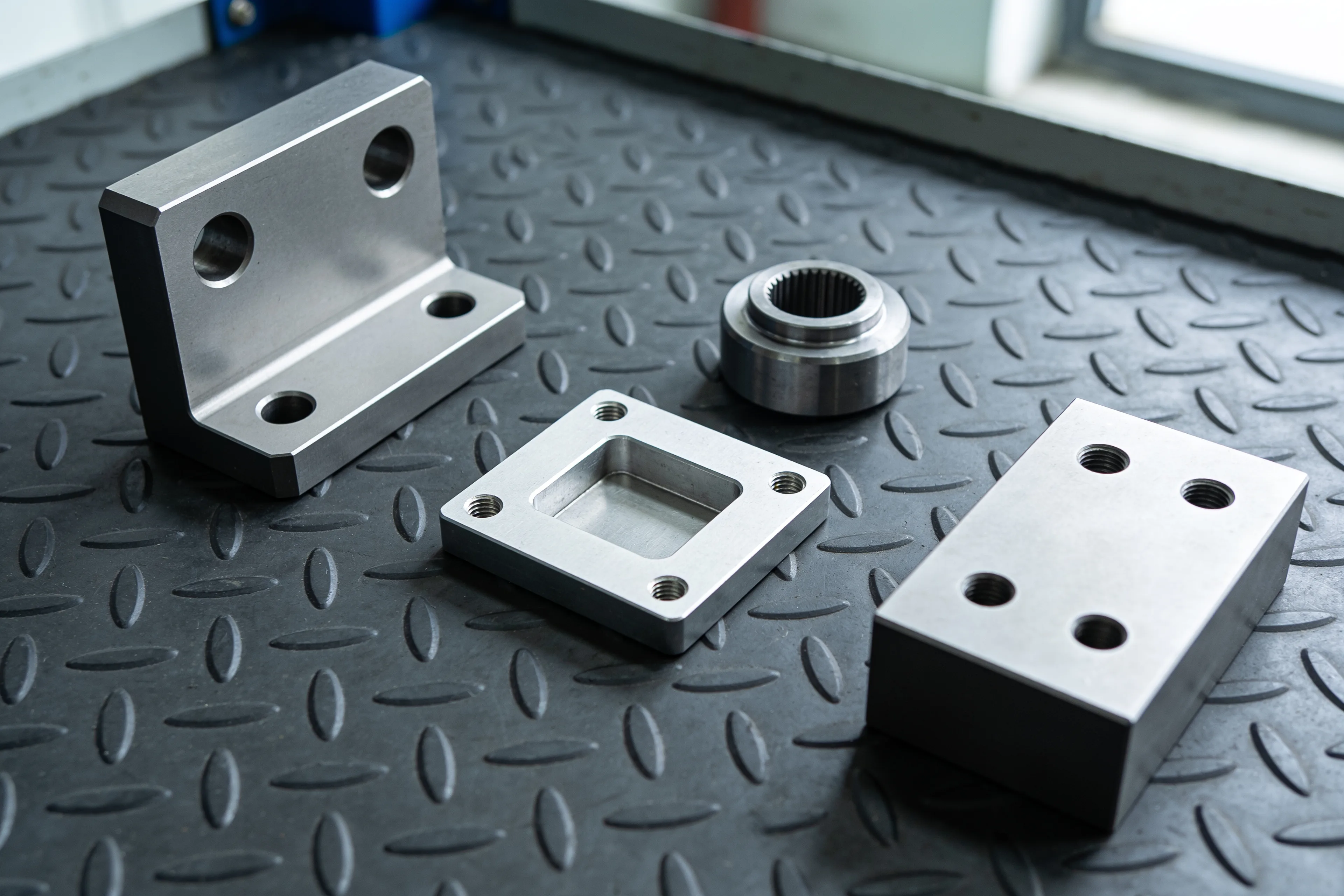 Gefräste und gedrehte Einzelteile aus Stahl und Aluminium auf einer Riffelblechmatte