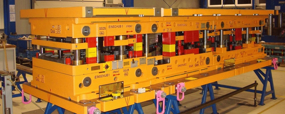 Folgeverbundwerkzeug mit orangefarbenen Platten auf Montageböcken